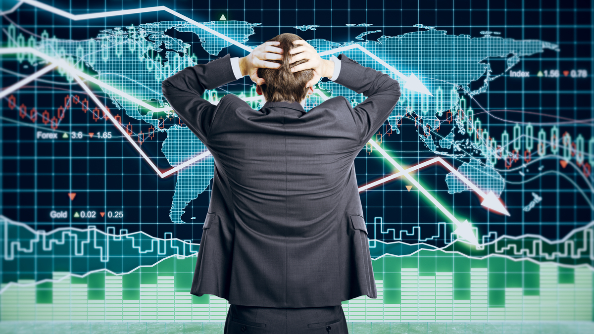 Picture of a man with his hands on head because he's puzzled by contradictory financial indicators