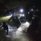 Rescue team in Thailand looking for young soccer players and their coach walk through a cave.