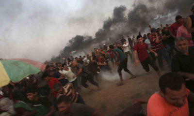 Photo of protesters running from tear gas at the Gaza Strip border