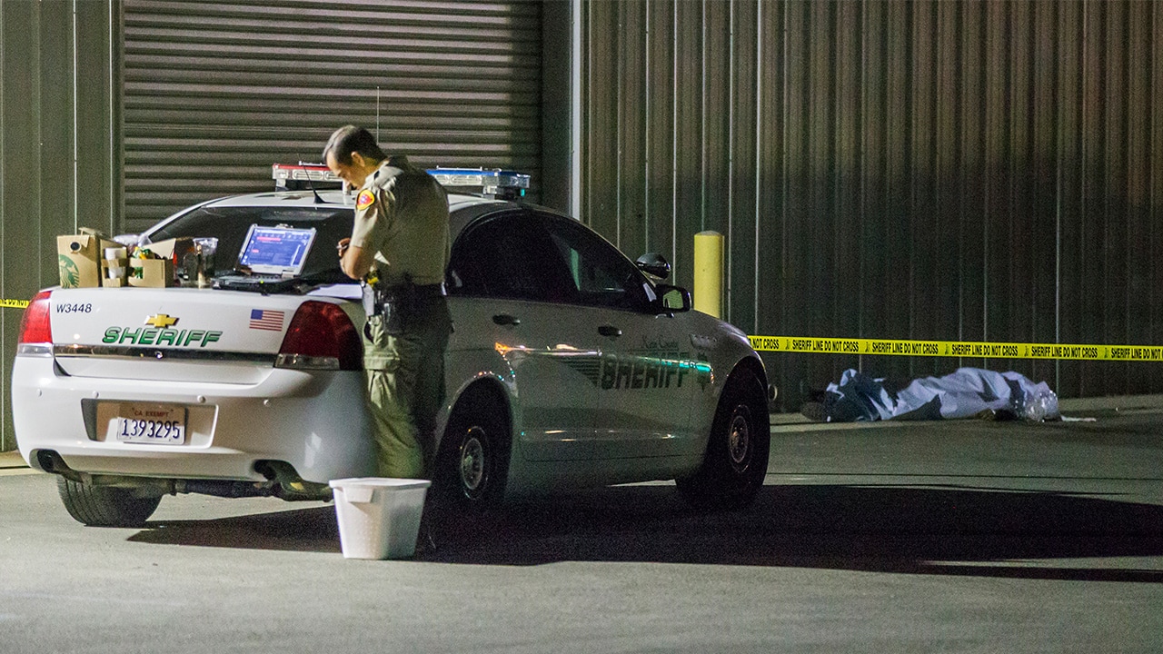 Photo of Kern County sheriff's deputy stands near an area where a shooting victim lies