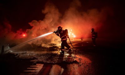Photo of a firefighter spraying the remains of a vehicle