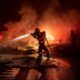 Photo of a firefighter spraying the remains of a vehicle