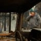 Photo of a wildfire victim wiping his eyes as he walks by a burned car