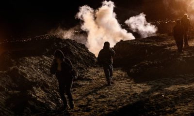 Photo of migrants running from tear gas at the US-Mexico border in Tijuana