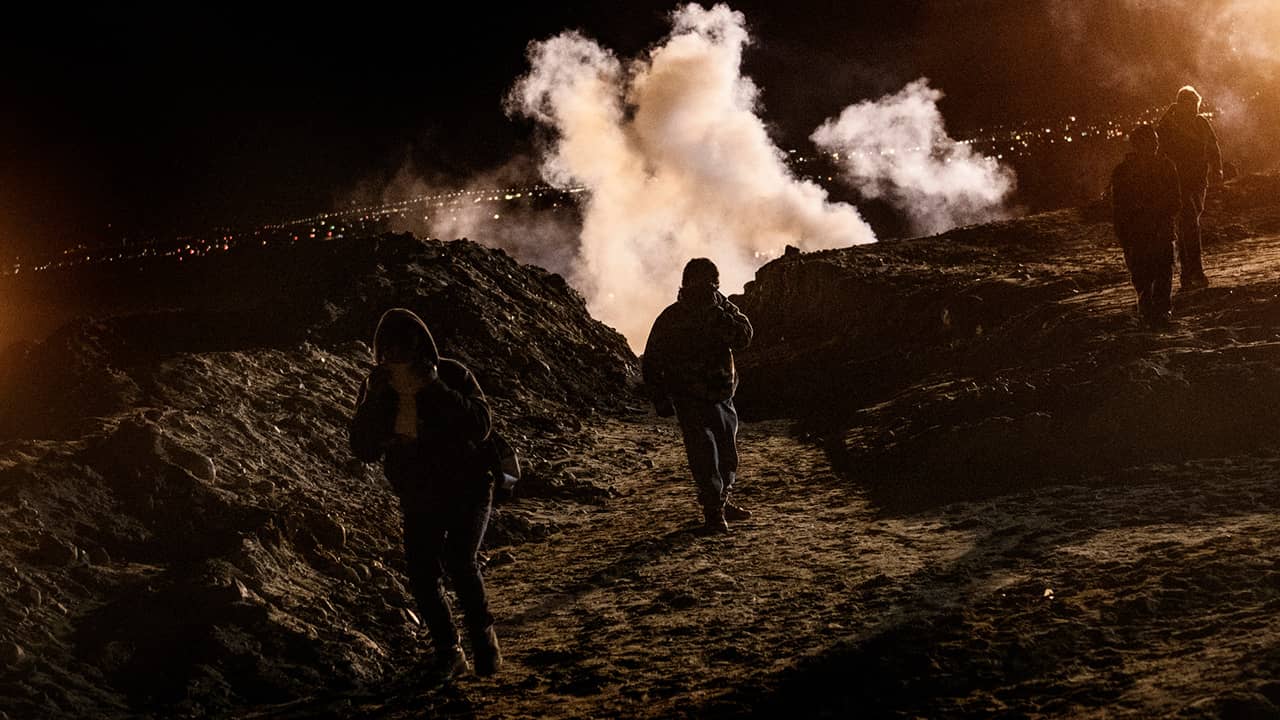 Photo of migrants running from tear gas at the US-Mexico border in Tijuana