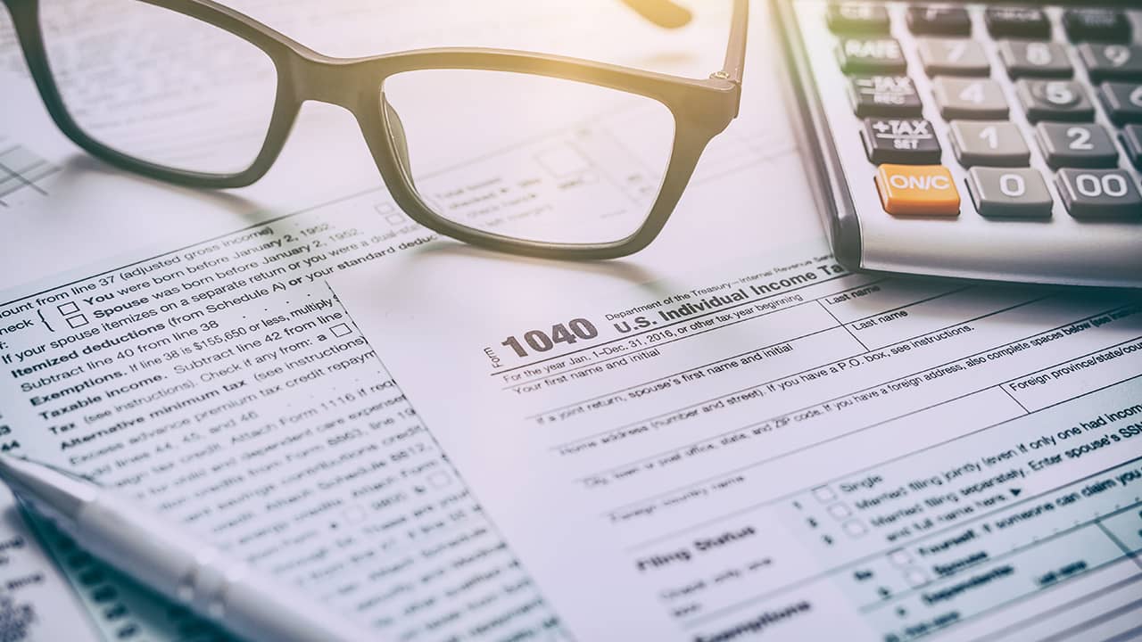Photo of tax form, glasses, and a calculator