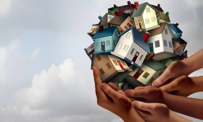 Composite of hands lifting up several toy houses. Image meant to convey affordable housing