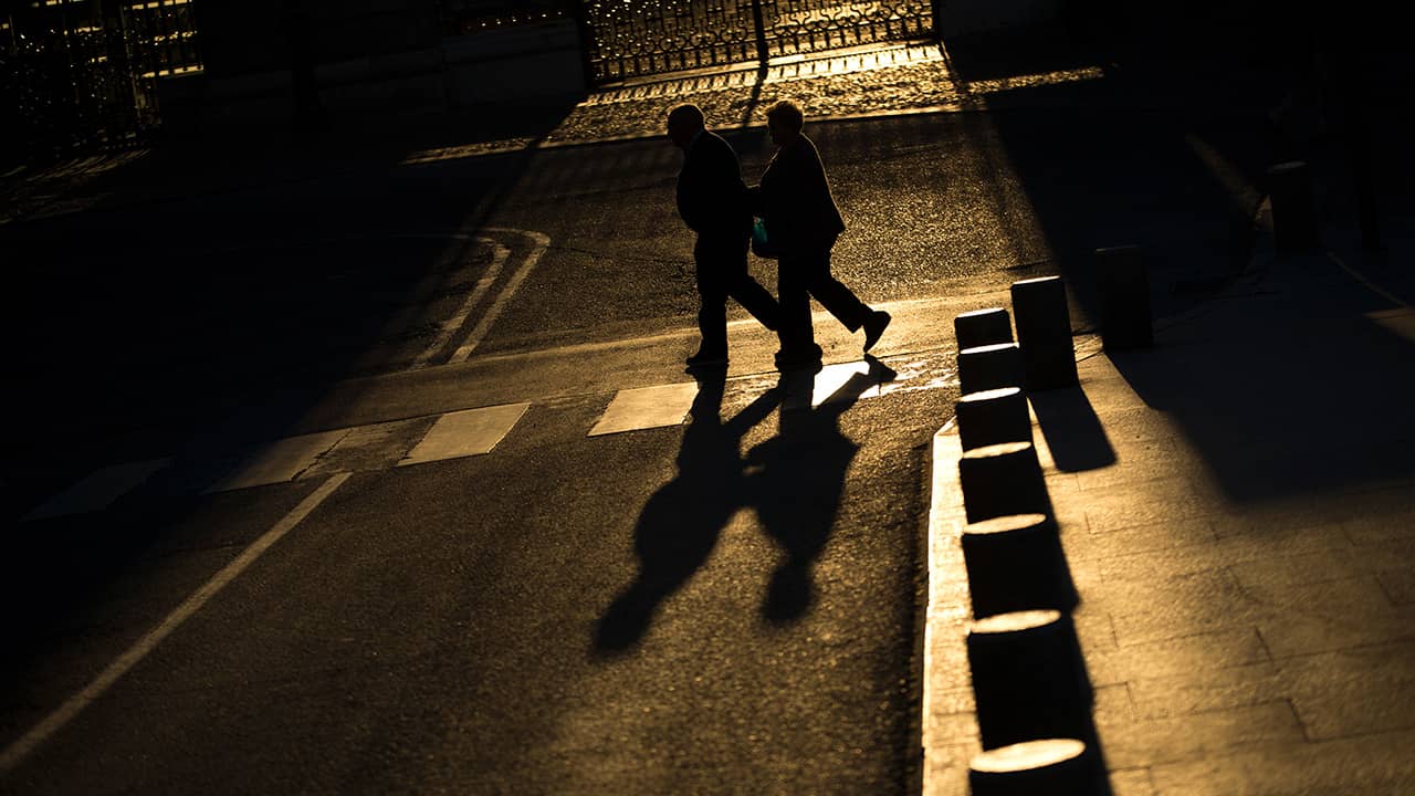 Photo of elderly couple walking across a street