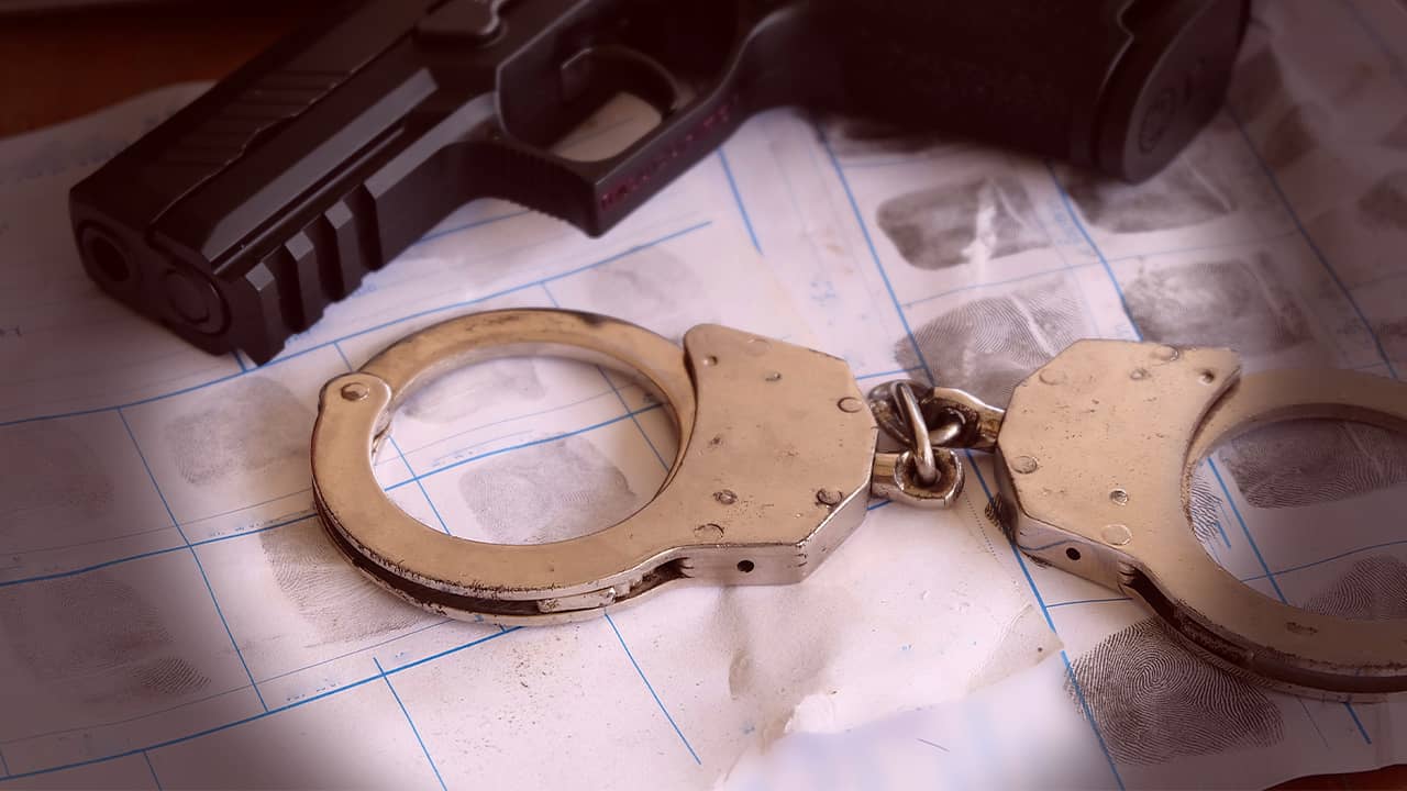 Photo of handcuffs, handgun and finger prints and fin