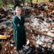 Photo of Sean Newsom posing at the burnout remains of his home in Paradise, CA