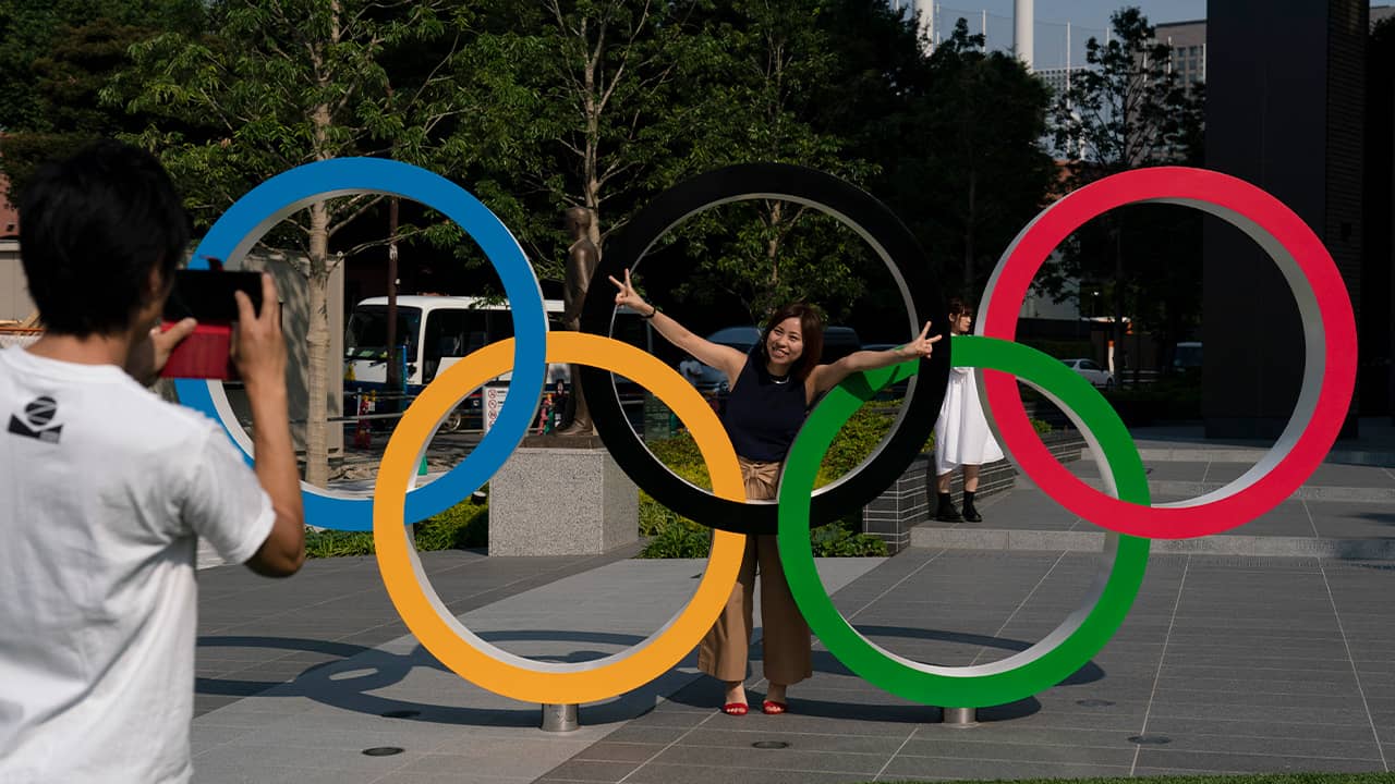 Photo of Tokyo resident taking a picture of his wife with the Olympic rings in Tokyo