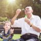 Photo of child with older man blowing bubbles in a park