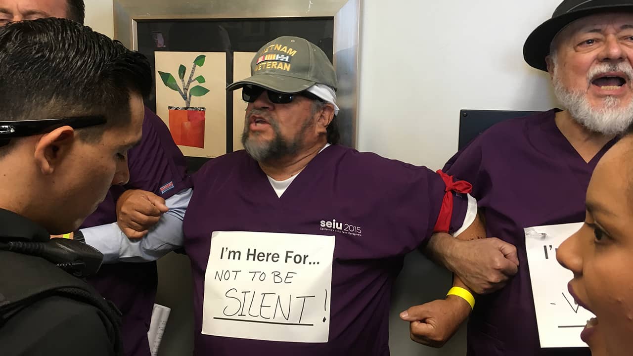 Photo of Robert De La Cruz (left) and Robert Navarro linking arms in protest