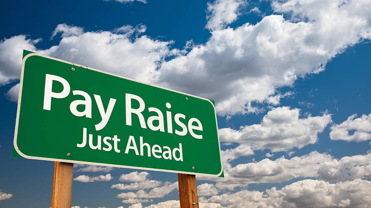Composite image of a pay raise ahead sign and blue skies
