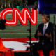 Photo of a journalist recording a video near a CNN sign