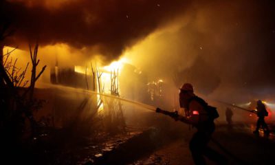 Photo of firefighters trying to hose down flames as homes burn