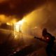 Photo of firefighters trying to hose down flames as homes burn