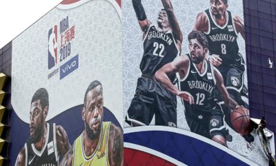Photo of a worker taking down a billboard advertising an NBA preseason basketball game