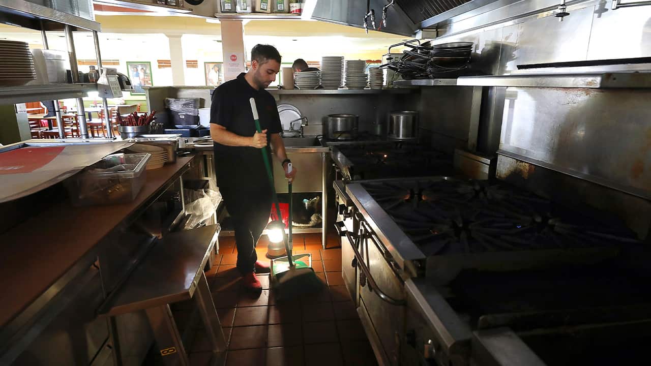 Photo of Salvador Espinosa sweeps in the kitchen of Mary's Pizza Shack