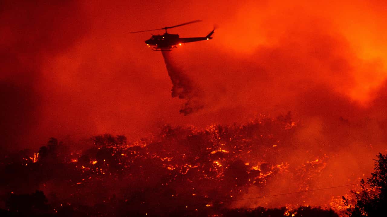 Photo of a helicopter dropping water on the Cave Fire