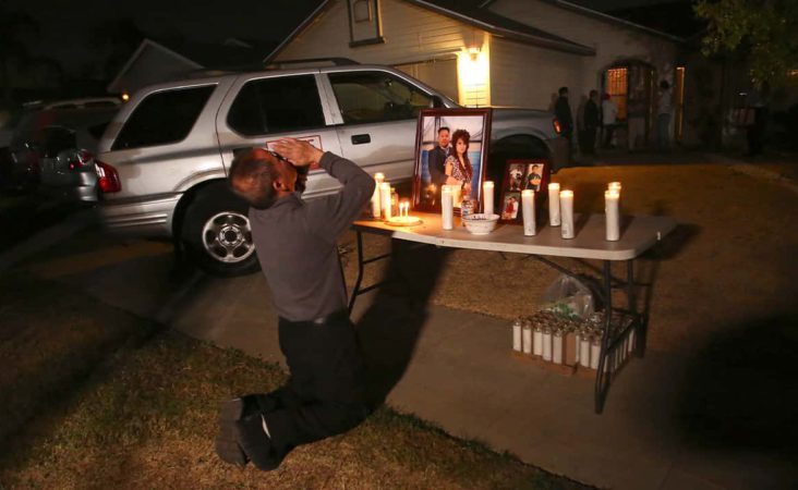 In this photo taken Monday, Nov. 18, 2019, Neej Xiong, uncle of shooting victim Kou Xiong, prays in front of a memorial during a candlelight vigil in Fresno, Calif. A close-knit Hmong community was in shock after gunmen burst into a California backyard gathering and shot 10 men, killing four. "We are right now just trying to figure out what to do, what are the next steps. How do we heal, how do we know what's going on," said Bobby Bliatout, a community leader. (Larry Valenzuela/The Fresno Bee via AP)