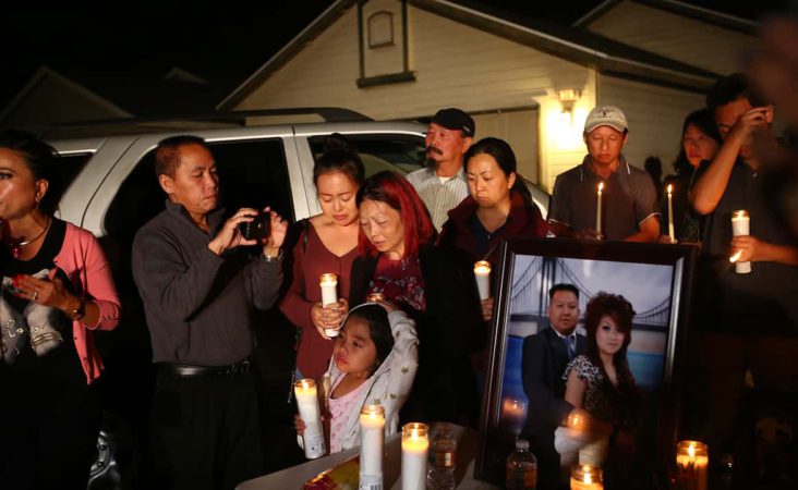 In this photo taken Monday, Nov. 18, 2019, the wife and young daughter of shooting victim Kou Xiong stand among the crowd during the candle light vigil in his honor outside their home in Fresno, Calif. A close-knit Hmong community was in shock after gunmen burst into a California backyard gathering and shot 10 men, killing four. "We are right now just trying to figure out what to do, what are the next steps. How do we heal, how do we know what's going on," said Bobby Bliatout, a community leader. (Larry Valenzuela/The Fresno Bee via AP)