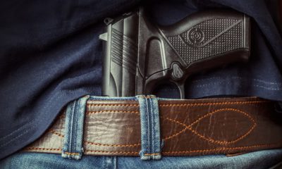 Photo of a man with a gun tucked under his belt in back