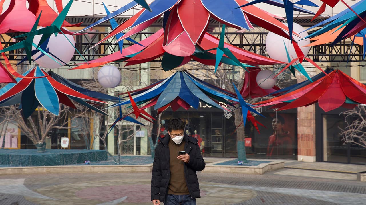 Photo of a man using his phone as he walks in Beijing, China