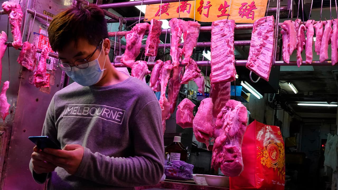 Photo of a man wearing a face mask in front of a meat booth in Hong Kong