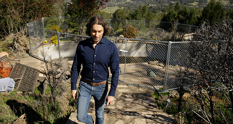 Photo of Jason Meeks walking through the remains of his hime in Santa Rosa, Calif.