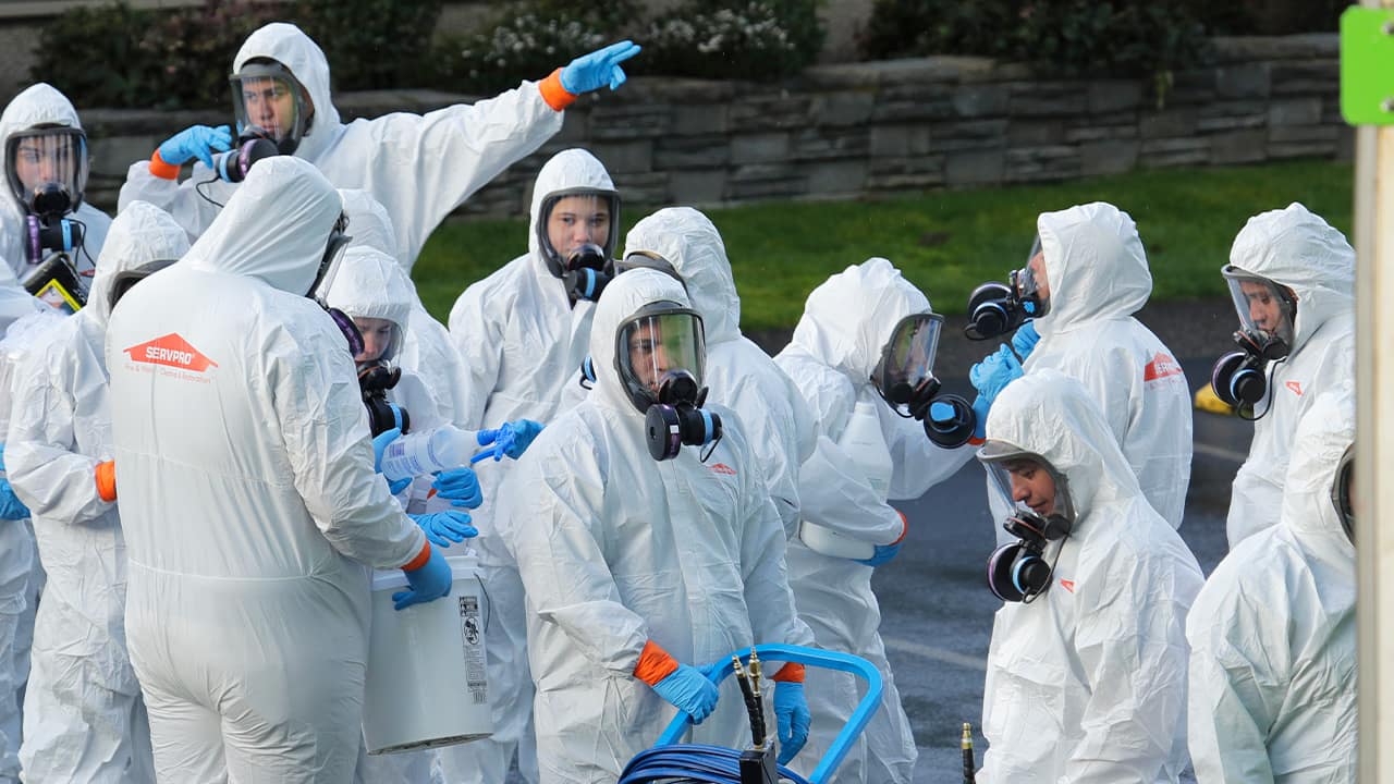 Photo of Workers from a Servpro disaster recovery team wearing protective suits and respirators