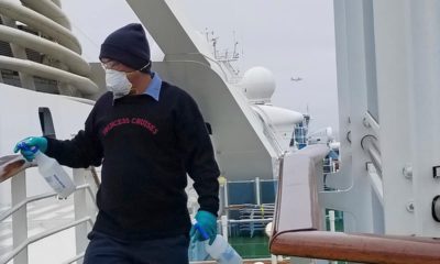 Photo of a cruise ship worker cleaning a railing