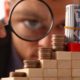 Photo of a man looking through a magnifying glass at small amounts of moneylas