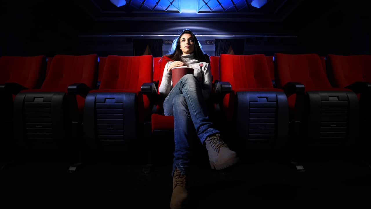 Photo of a woman who is the only one at a movie theateritting in