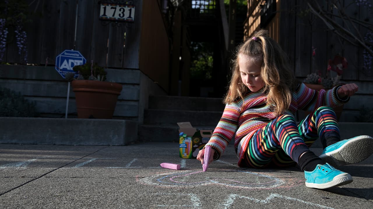Photo of a young girl drawing with chalk