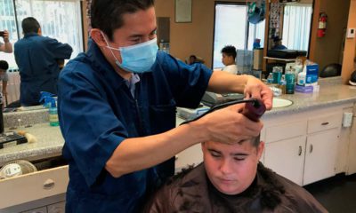 Image of a Madera, California barber wearing a mask while cutting a customer's hair