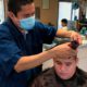 Image of a Madera, California barber wearing a mask while cutting a customer's hair