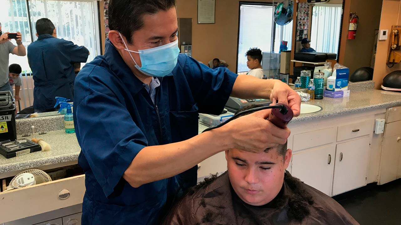 Image of a Madera, California barber wearing a mask while cutting a customer's hair