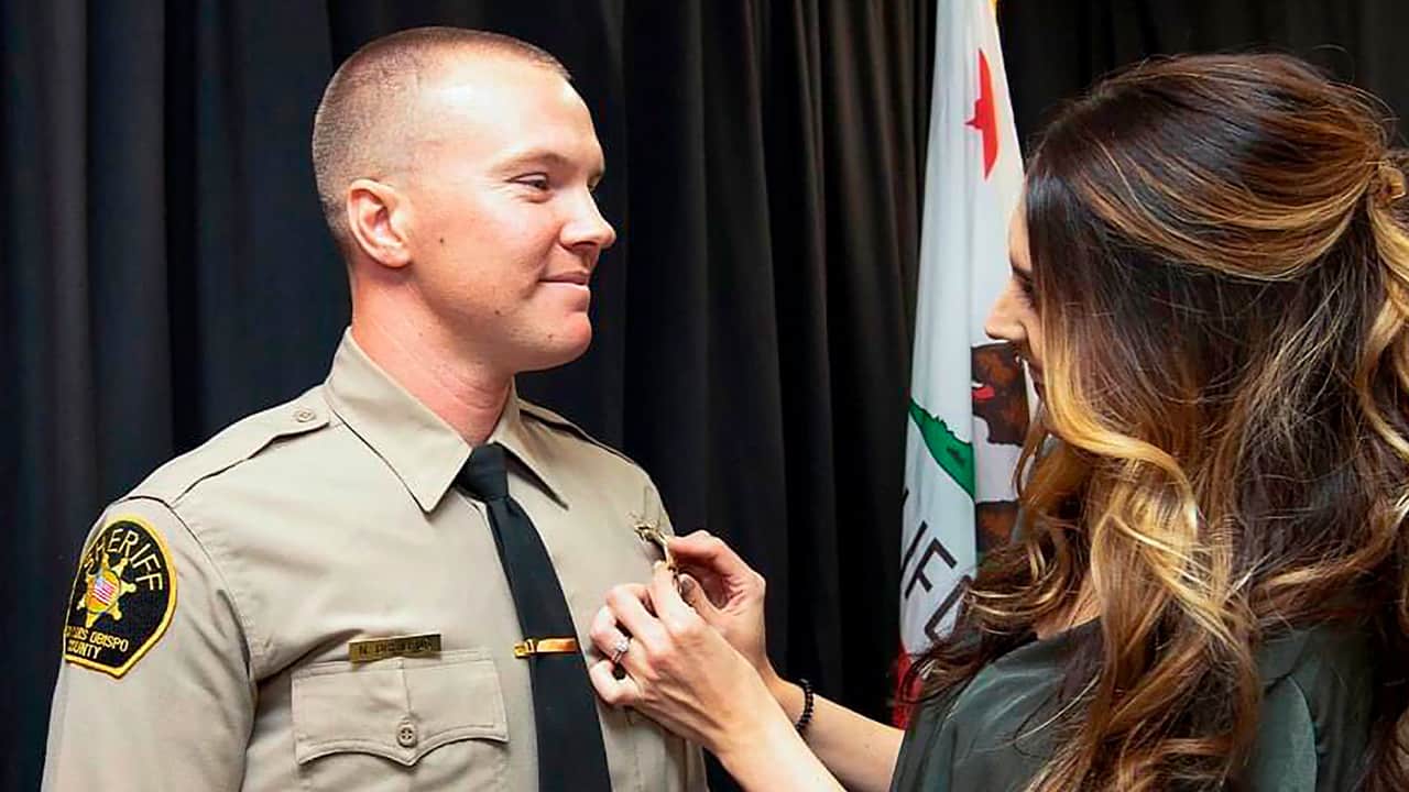 Photo of Deputy Nicholas Dreyfus receiving his badge from his wife