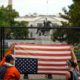 Photo of people holding a flag upside down at the white house