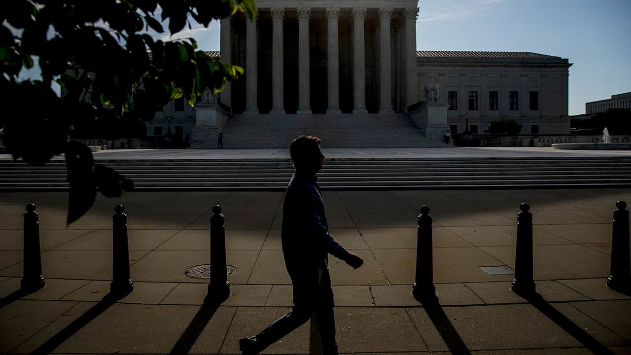 Photo fo a man walking past the Supreme Court
