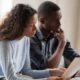 Image of a young African American couple poring over their monthly expenses