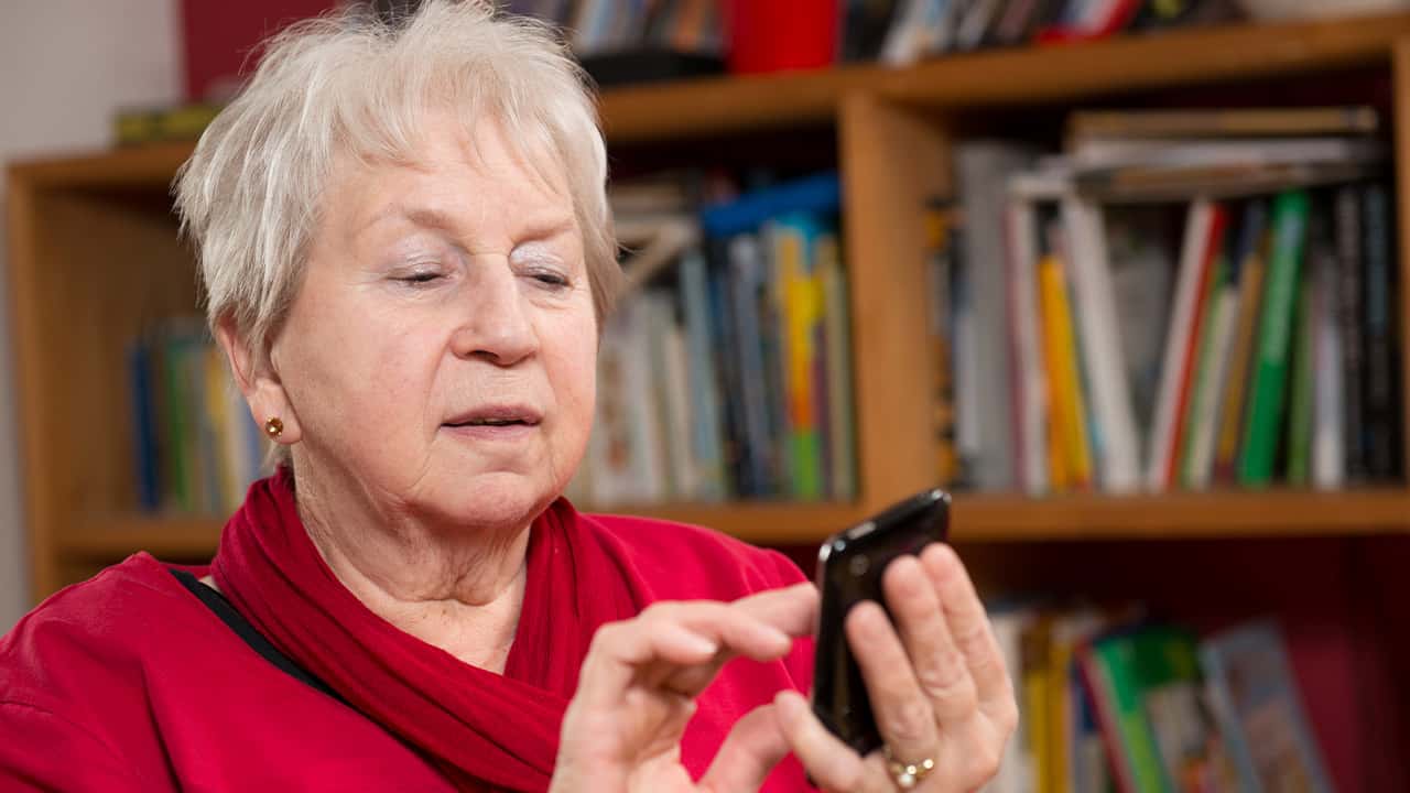 Image of a woman dialing a smartphone in a room filled with books
