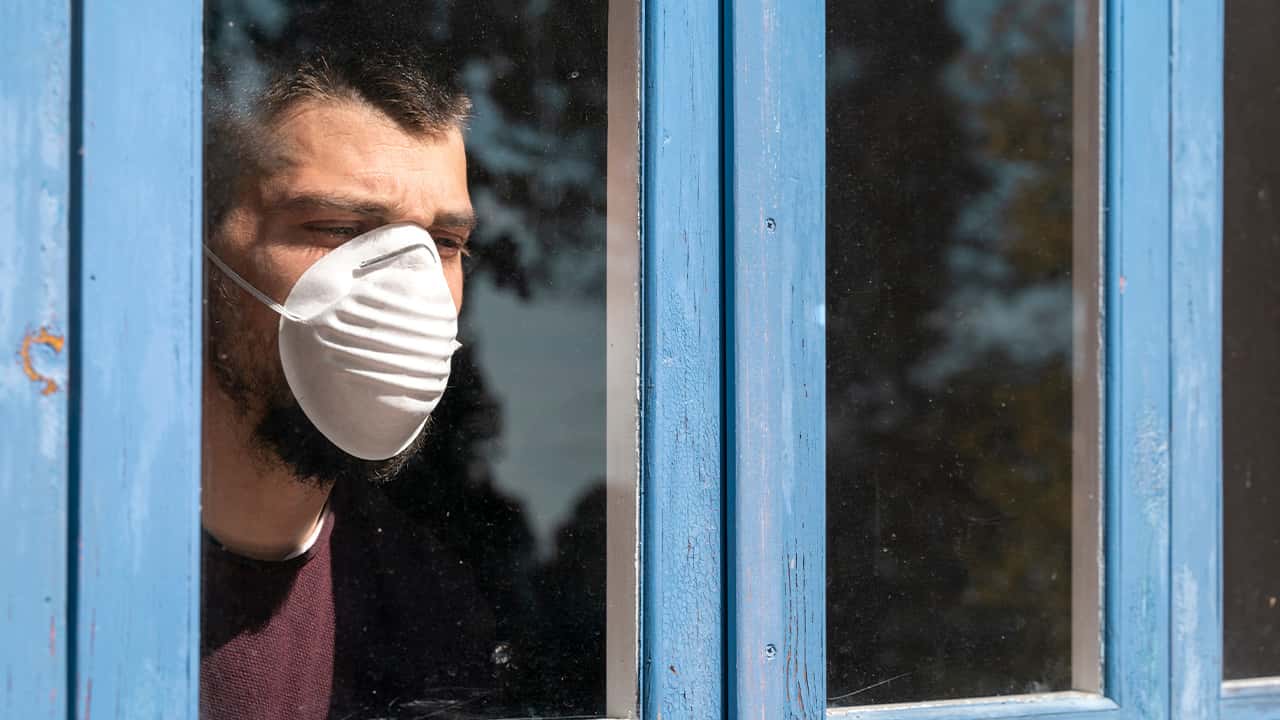 Image of a patient with a mask looking out of a hospital window